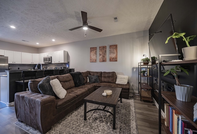 living room with dark hardwood / wood-style flooring, ceiling fan, sink, and a textured ceiling