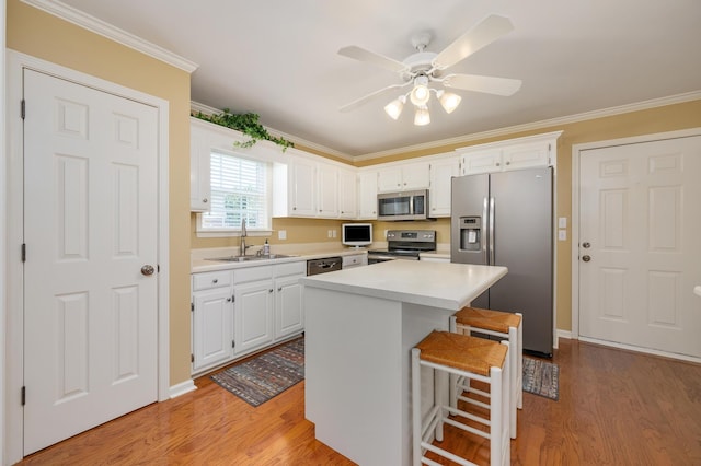 kitchen with ceiling fan, sink, a kitchen island, appliances with stainless steel finishes, and light hardwood / wood-style flooring