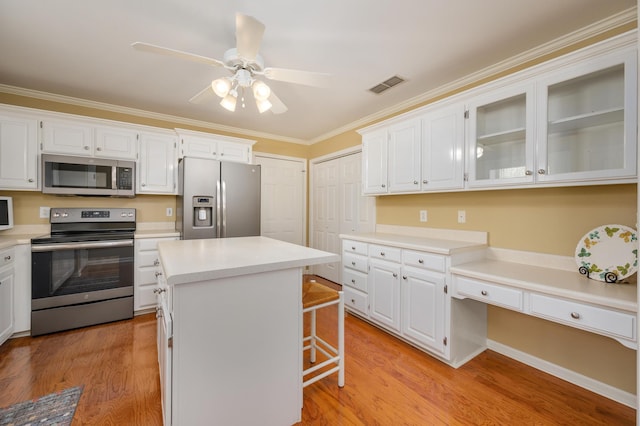 kitchen featuring a kitchen island, ceiling fan, stainless steel appliances, light hardwood / wood-style flooring, and ornamental molding