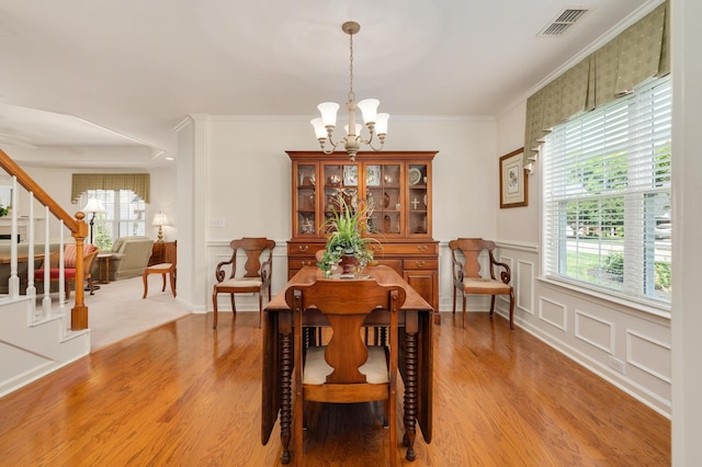 dining space featuring plenty of natural light, crown molding, a notable chandelier, and light hardwood / wood-style flooring