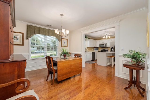 dining area with crown molding, ceiling fan with notable chandelier, and light wood-type flooring