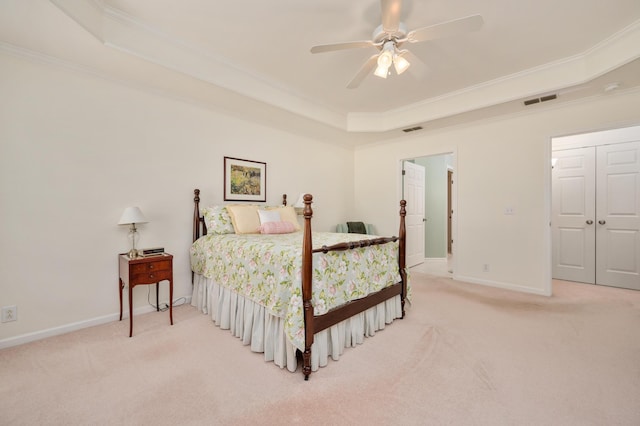 carpeted bedroom with a closet, ceiling fan, a raised ceiling, and ornamental molding