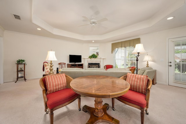 carpeted living room with crown molding, ceiling fan, and a tray ceiling