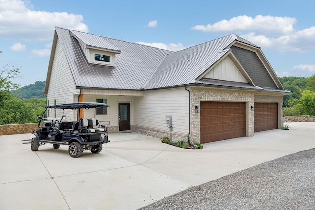 view of front of house with an attached garage, metal roof, and concrete driveway