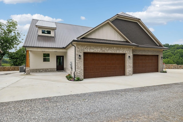 view of front facade featuring board and batten siding, metal roof, driveway, and central air condition unit