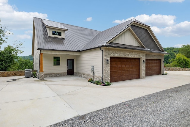 view of front of property featuring concrete driveway, metal roof, an attached garage, central AC, and board and batten siding