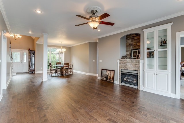 unfurnished living room featuring a stone fireplace, decorative columns, dark hardwood / wood-style floors, and ceiling fan with notable chandelier