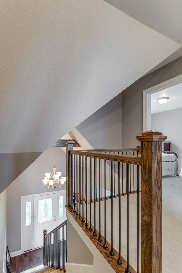 corridor featuring light carpet, lofted ceiling, and a chandelier