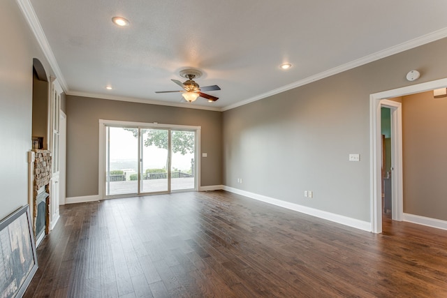 unfurnished room with ornamental molding, a fireplace, ceiling fan, and dark wood-type flooring