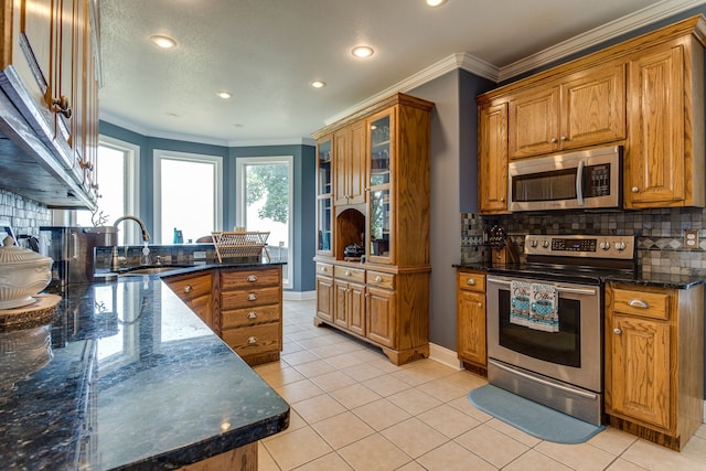 kitchen with appliances with stainless steel finishes, backsplash, and dark stone countertops