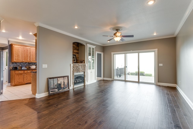 unfurnished living room with ceiling fan, ornamental molding, light tile floors, and a stone fireplace