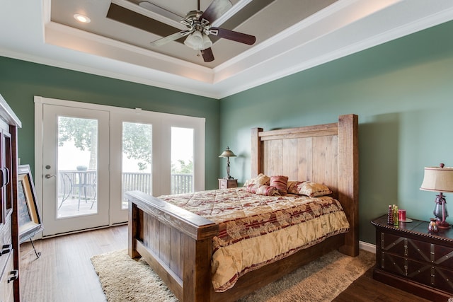 bedroom featuring hardwood / wood-style flooring, ceiling fan, crown molding, a tray ceiling, and access to outside