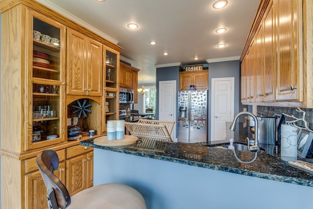 kitchen featuring dark stone counters, tasteful backsplash, stainless steel appliances, a chandelier, and crown molding