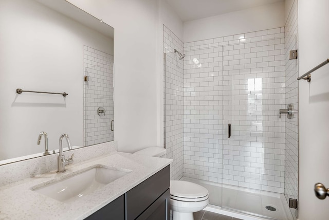 bathroom with toilet, a shower with door, tile floors, and vanity with extensive cabinet space