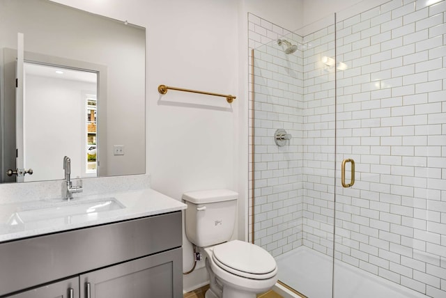 bathroom with toilet, a shower with door, and vanity with extensive cabinet space