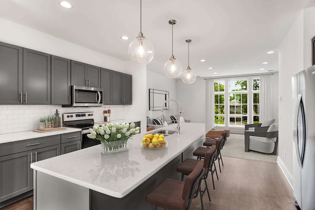 kitchen featuring backsplash, light hardwood / wood-style floors, stainless steel appliances, and gray cabinets