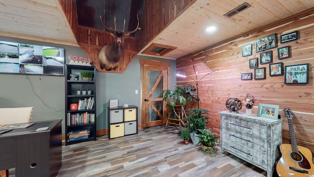 office area with light hardwood / wood-style floors, wooden ceiling, and wooden walls