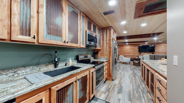 kitchen with sink, light stone counters, wood ceiling, appliances with stainless steel finishes, and light wood-type flooring