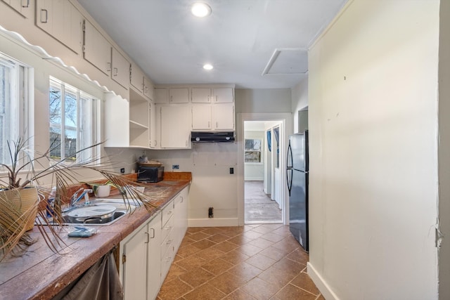 kitchen with tile countertops, dark tile patterned floors, sink, and fridge