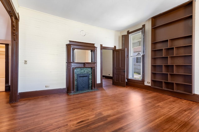 unfurnished living room with built in features, dark wood-type flooring, and a premium fireplace