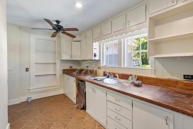 kitchen with tile countertops, dishwasher, sink, ceiling fan, and white cabinetry