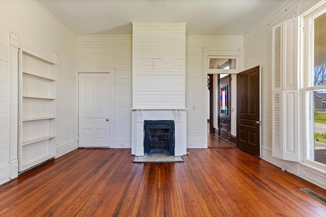 unfurnished living room featuring built in features and dark wood-type flooring