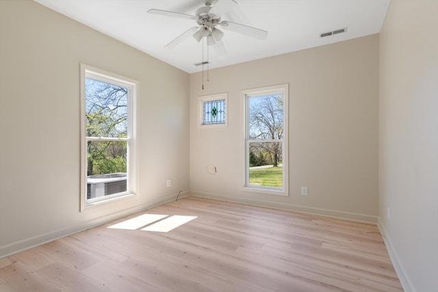 unfurnished room featuring a wealth of natural light, ceiling fan, and light hardwood / wood-style floors