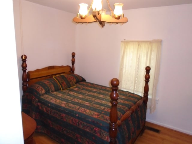 bedroom with an inviting chandelier and dark wood-type flooring