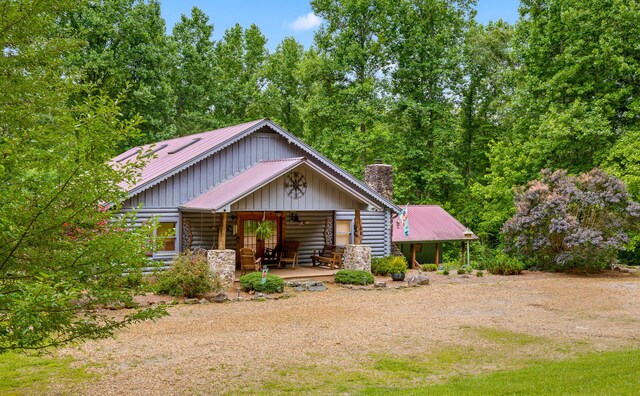 view of front of property featuring a chimney, metal roof, log exterior, and a porch