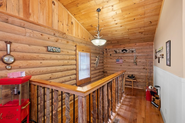 hallway featuring lofted ceiling, visible vents, wood ceiling, an upstairs landing, and hardwood / wood-style floors