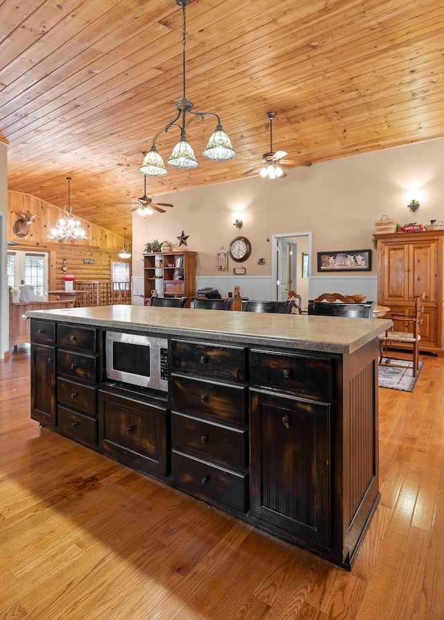 kitchen with open floor plan, light wood finished floors, stainless steel microwave, and vaulted ceiling