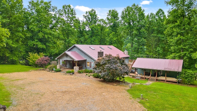 view of front of home featuring a front yard, metal roof, driveway, and a chimney