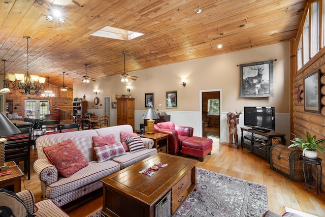 living room with a wainscoted wall, wood ceiling, lofted ceiling with skylight, hardwood / wood-style floors, and ceiling fan with notable chandelier