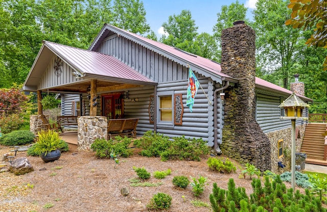 log home featuring board and batten siding, a chimney, metal roof, and log exterior