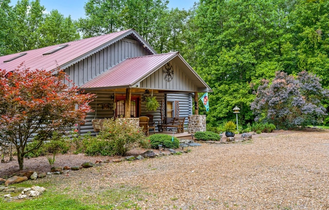 view of front facade featuring board and batten siding, metal roof, a porch, and log exterior