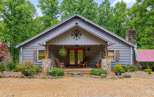 log home featuring french doors, a chimney, a porch, and log siding