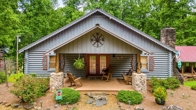 cabin with french doors, a chimney, and log siding