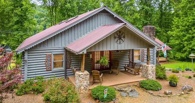 log cabin with covered porch, metal roof, log exterior, and a chimney