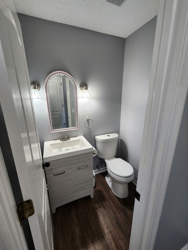 bathroom featuring toilet, a textured ceiling, large vanity, and hardwood / wood-style flooring