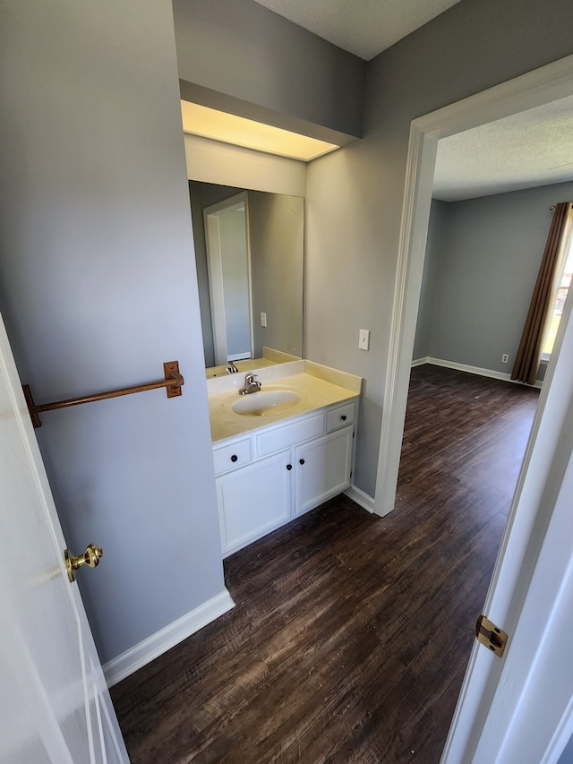 bathroom featuring a textured ceiling, hardwood / wood-style floors, and vanity with extensive cabinet space