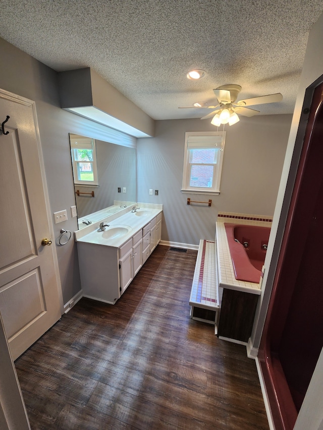 bathroom featuring hardwood / wood-style floors, ceiling fan, a textured ceiling, dual bowl vanity, and a tub