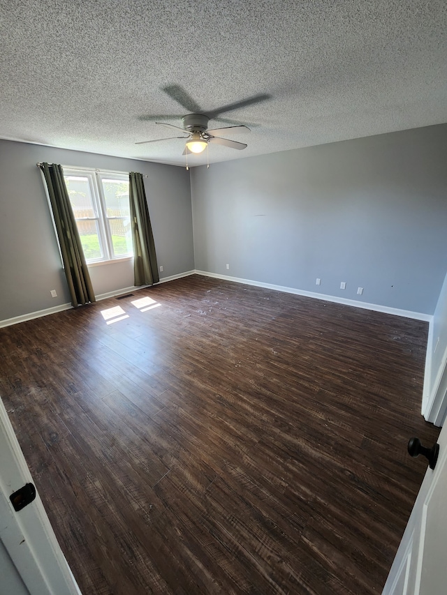 empty room with ceiling fan, dark wood-type flooring, and a textured ceiling