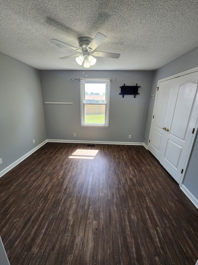 interior space featuring ceiling fan, dark wood-type flooring, and a textured ceiling