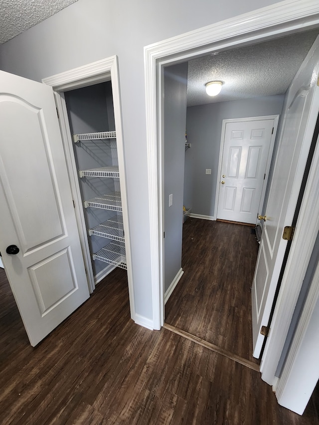 hall with a textured ceiling and dark hardwood / wood-style floors