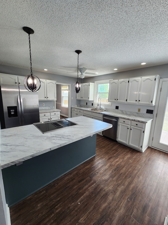 kitchen with a notable chandelier, stainless steel appliances, decorative light fixtures, white cabinetry, and dark hardwood / wood-style floors