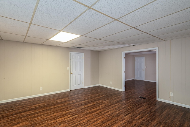 empty room featuring a paneled ceiling and dark hardwood / wood-style flooring