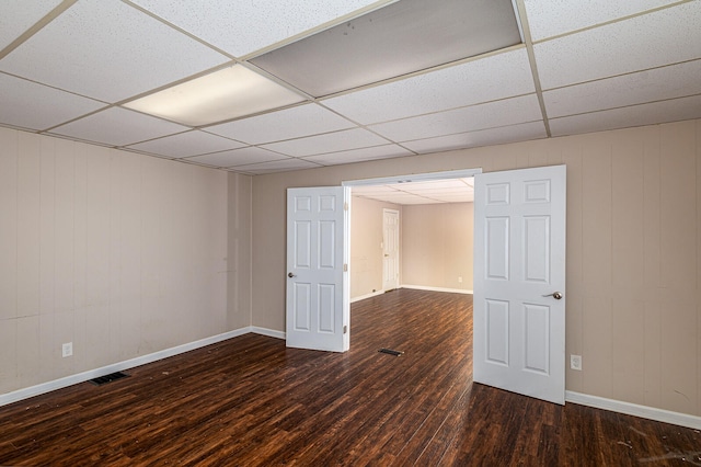 spare room featuring dark hardwood / wood-style floors and a drop ceiling