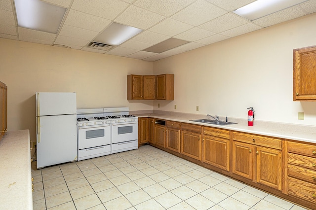 kitchen with white appliances, a drop ceiling, sink, and light tile floors