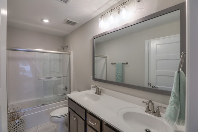 full bathroom featuring double sink, tile floors, bath / shower combo with glass door, toilet, and large vanity