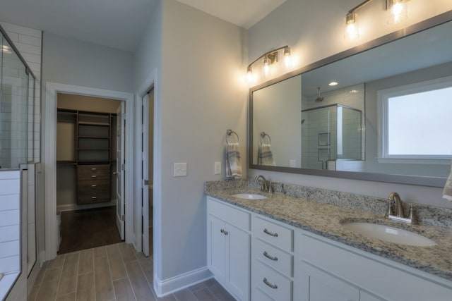 bathroom with walk in shower, hardwood / wood-style floors, dual sinks, and vanity with extensive cabinet space